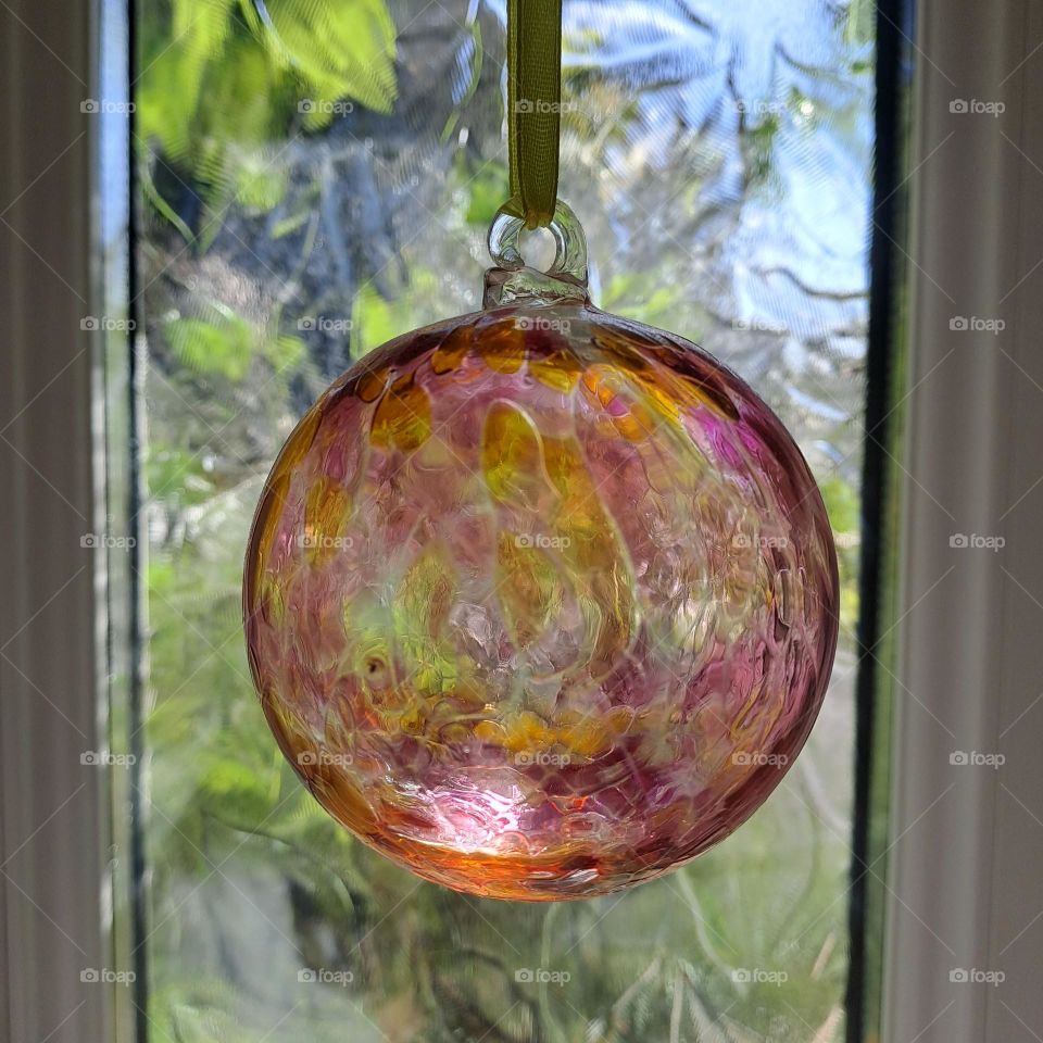 glass ball hanging in front of window natural light leaves behind window daylight