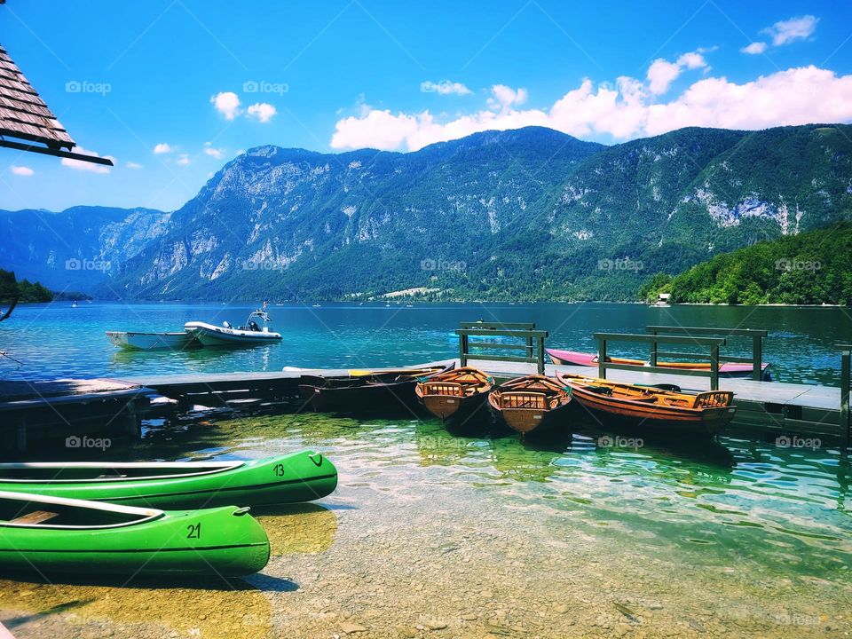 Scenic view of green Alps mountains against blue sky and beautiful lake in Slovenia. Summer time. Vacation. Landscape.