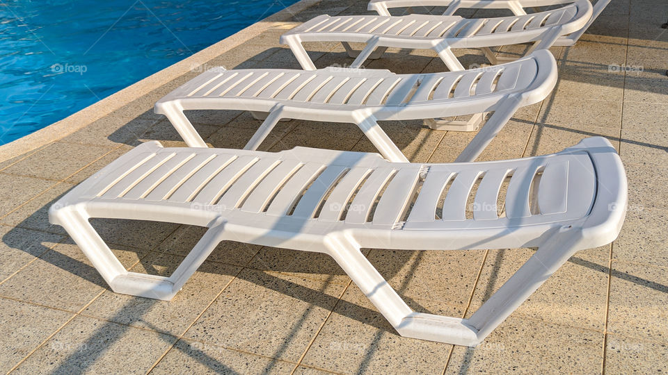 Row of free sunbeds at the swimming pool in a touristic resort.