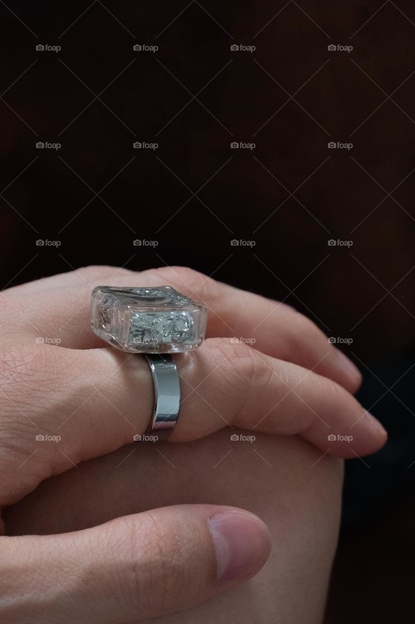 Ring with shimmer on a finger on a brown background