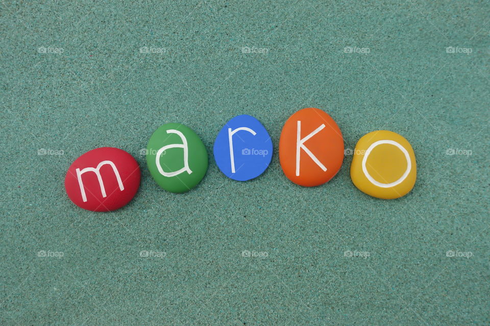 Marko, masculine given name composed with colored stones over green sand