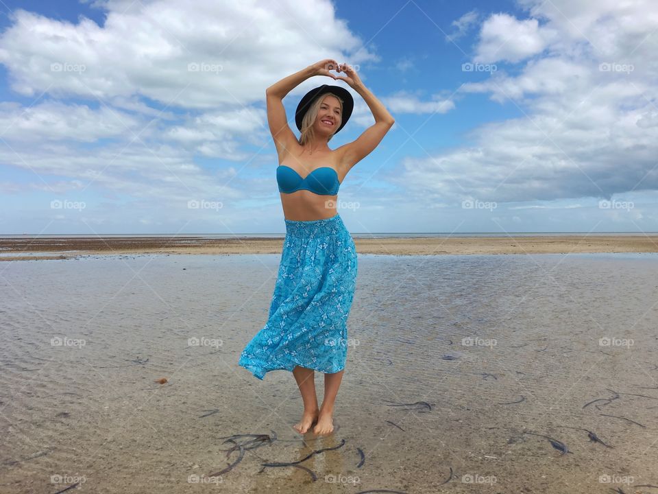 Woman making heart shape at beach