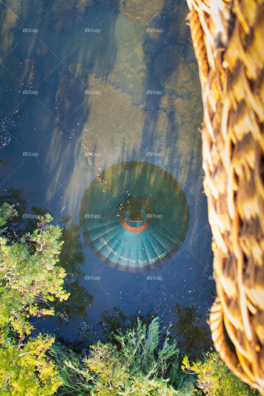 flying - hot air balloon basket and looking into balloon reflection in river below
