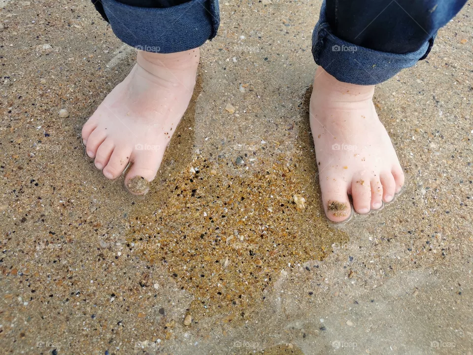 Petits pieds de bébé sur le sable à la mer.
Little baby feet on the sand at the sea