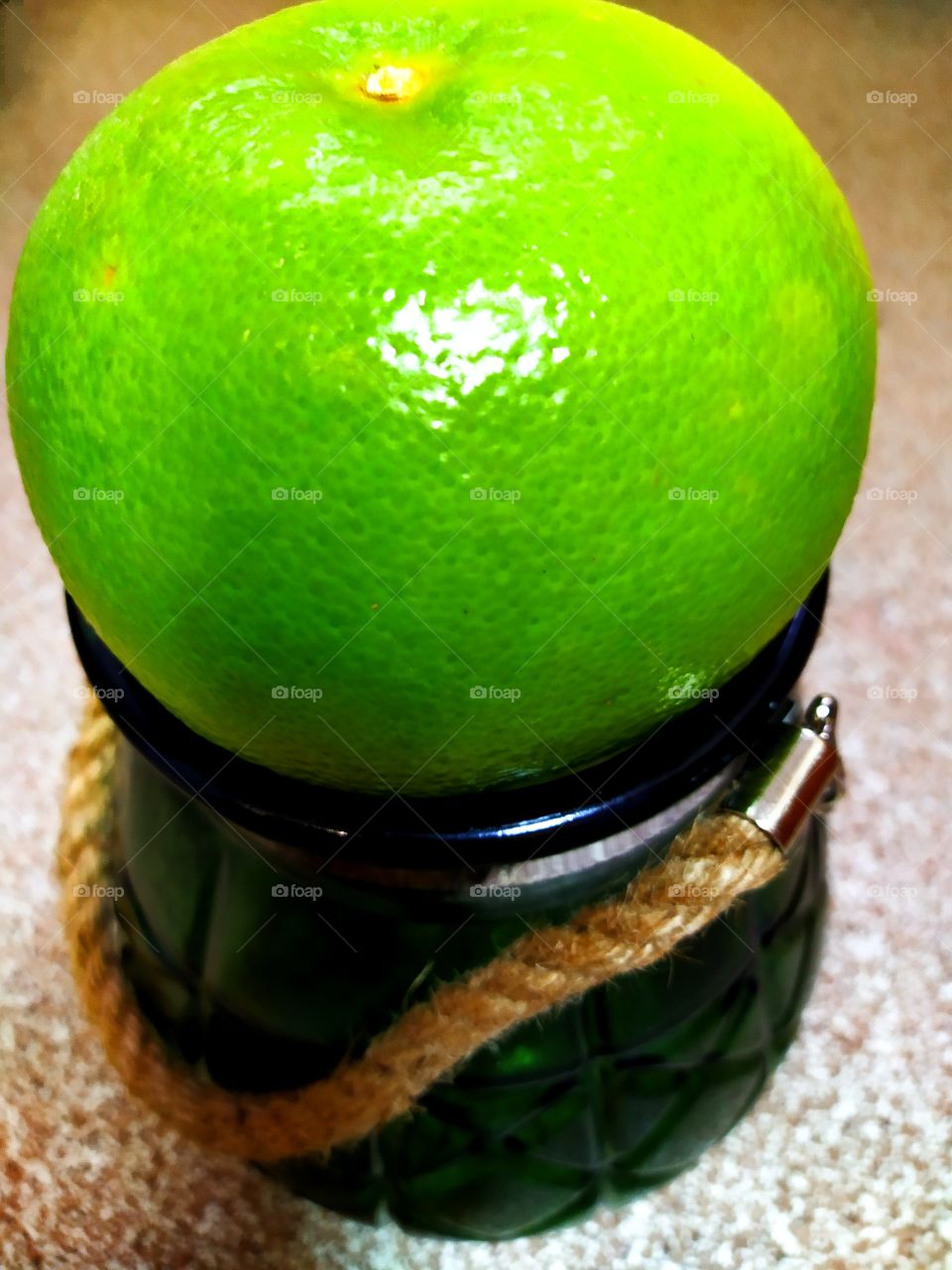 green grapefruit on a green glass vase with a rope handle