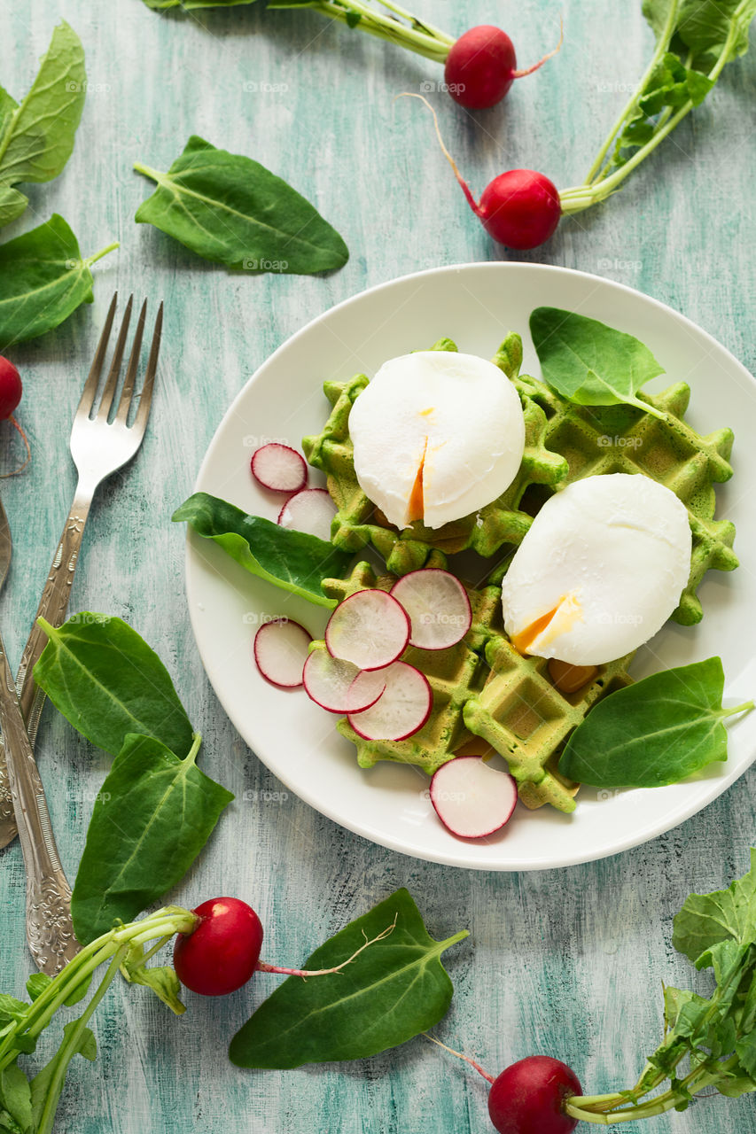 Spinach Belgian waffles with radishes, spinach leaves and poached eggs