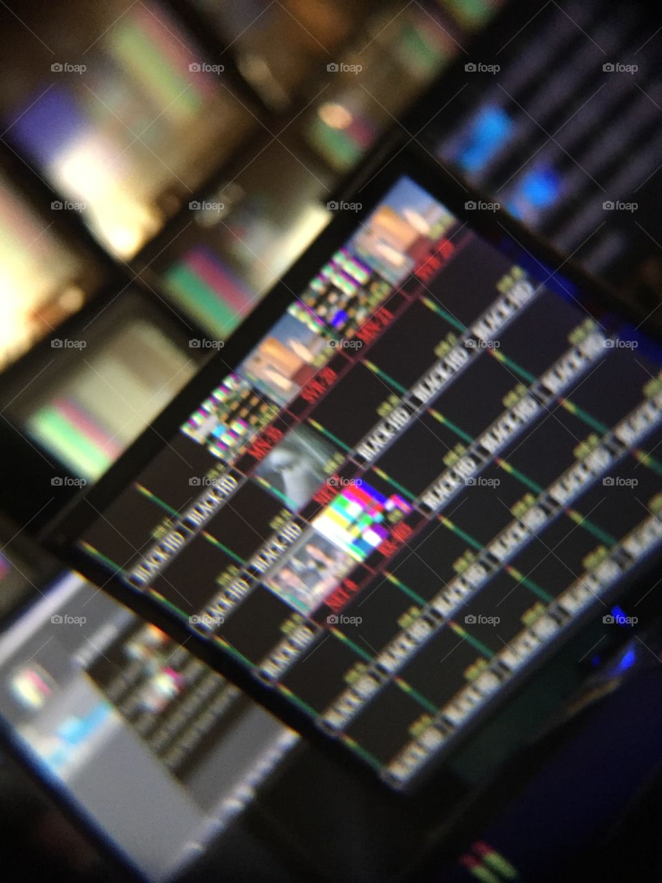Computer monitors in rows with color bars and shows but blurred enough so that nothing is recognizable.  