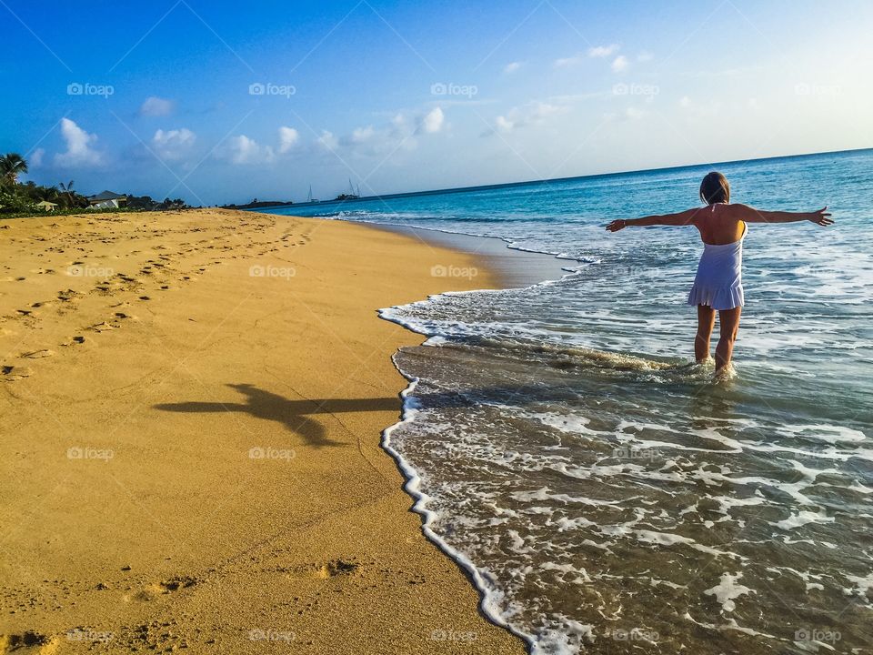 Cross shadow on the beach, reaching out to the sun