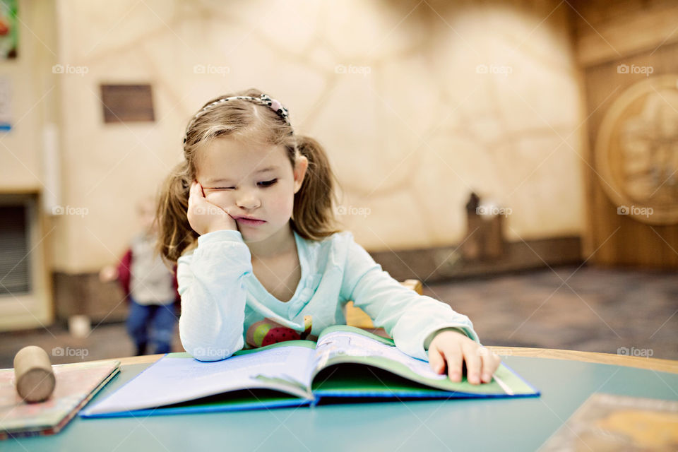 Little girl at the library looking bored 