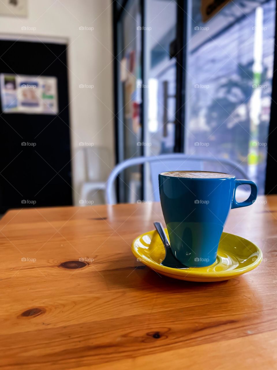 A cup of hot coffee in a baby blue mug in a cafe