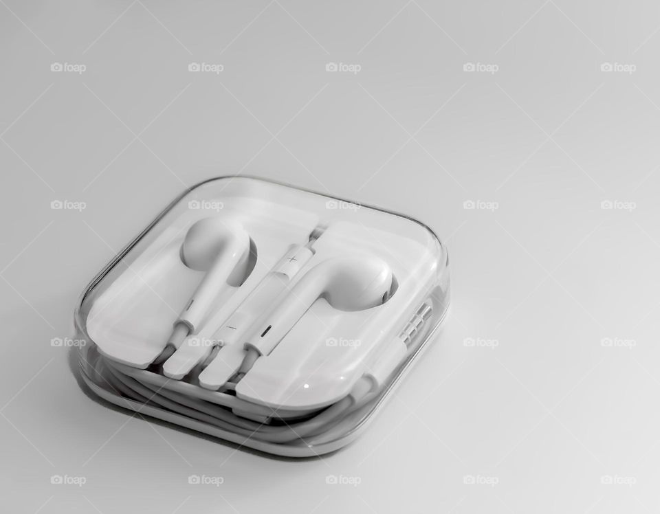 Apple wired earphones in their plastic box on off white background 