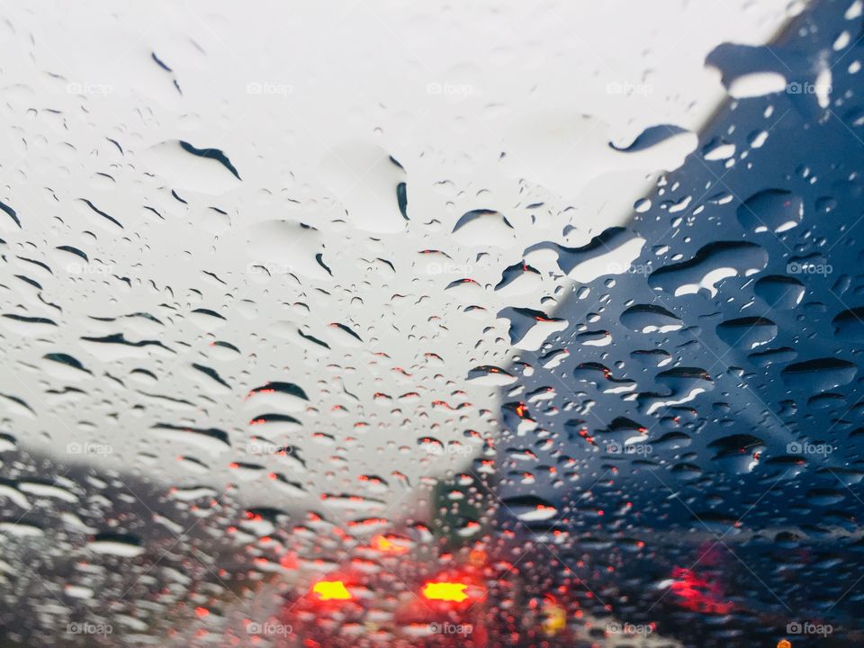 Raindrops on car windshield and traffic ahead 
