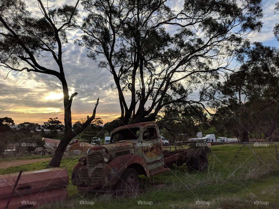 Rusty old truck against a setting sunset