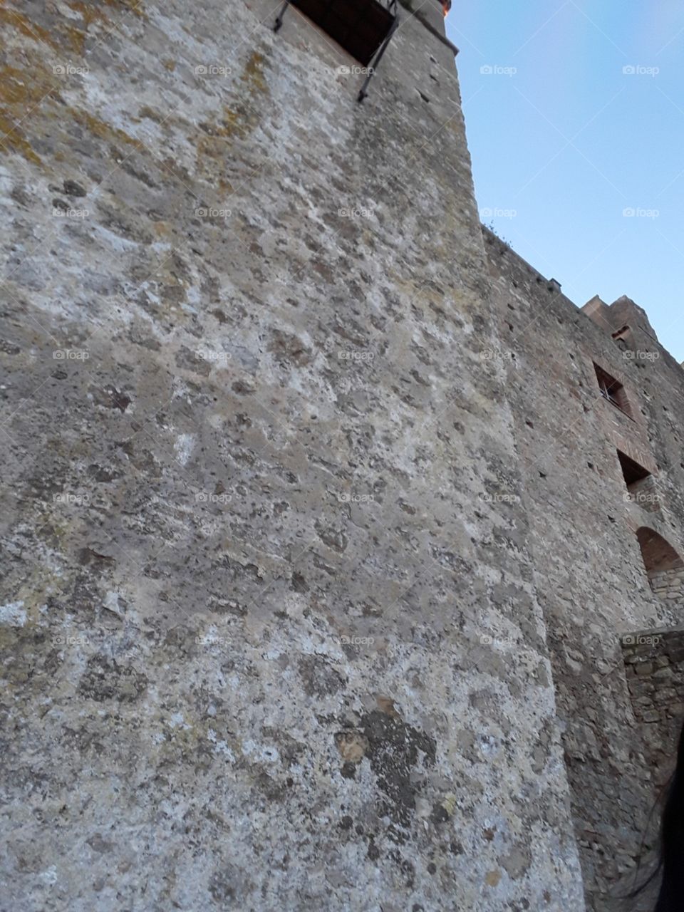 vista de un muro de ladrillos lateral con ventanas en lo alto perteneciente al Castillo del Castellar.  Cádiz, España