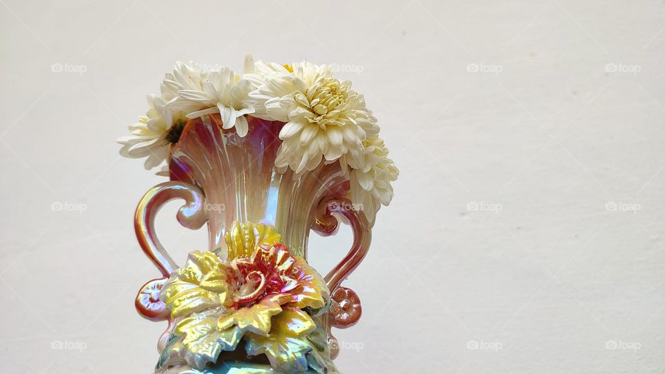 Beautiful white flowers in a colourful flowerpot with a flower sculpture, Flowers in a vase, colourful vase, white flowers in a vase