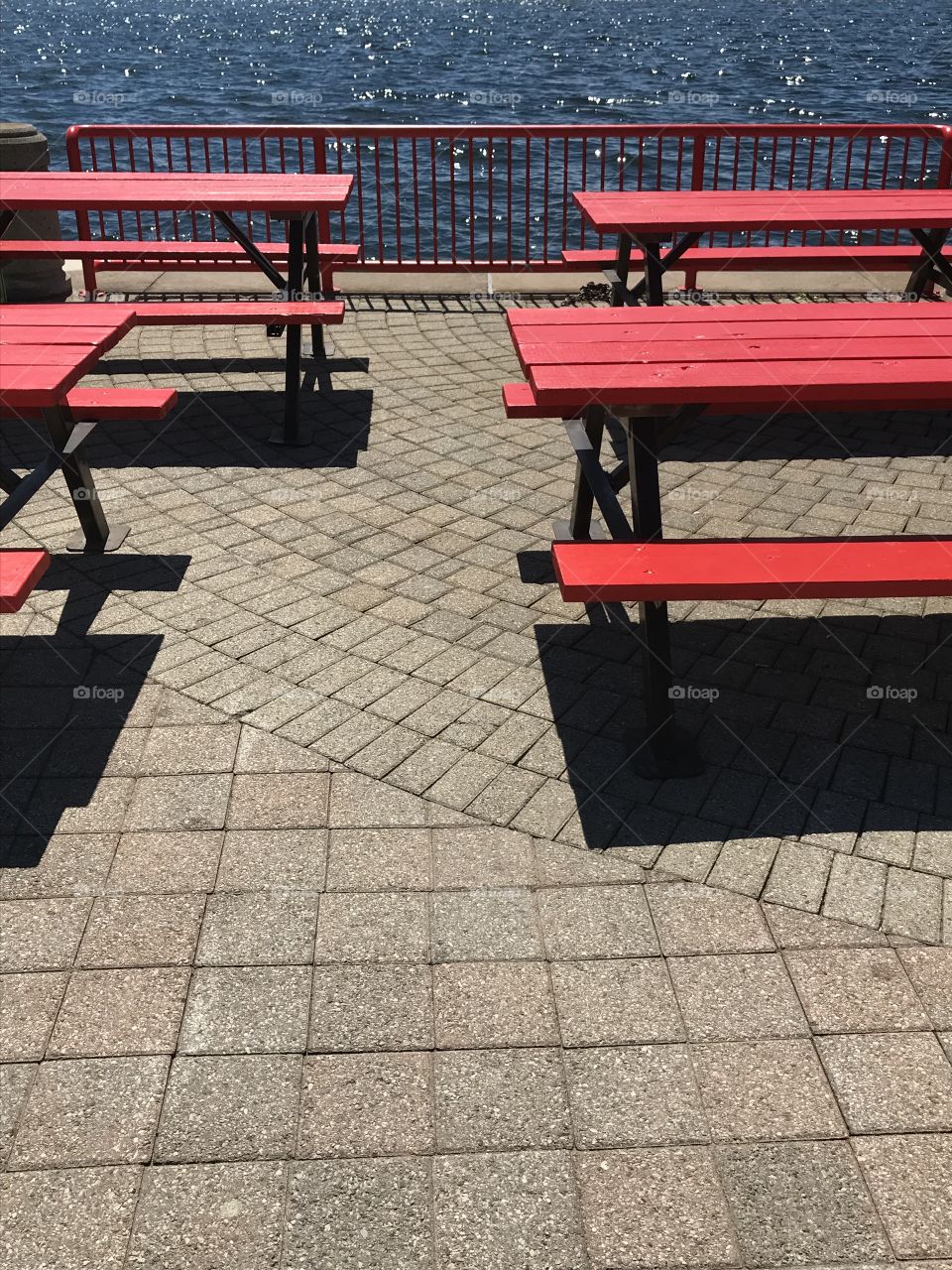 Red picnic benches near water