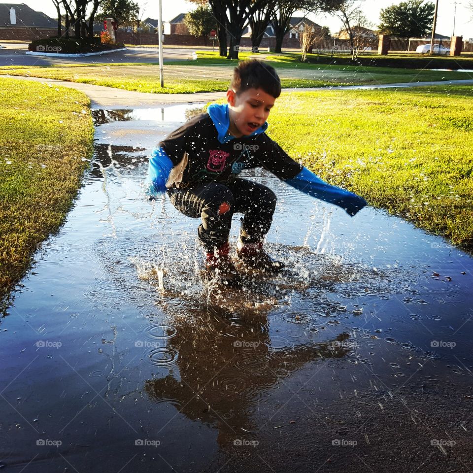 Little boy playing in rain puddle