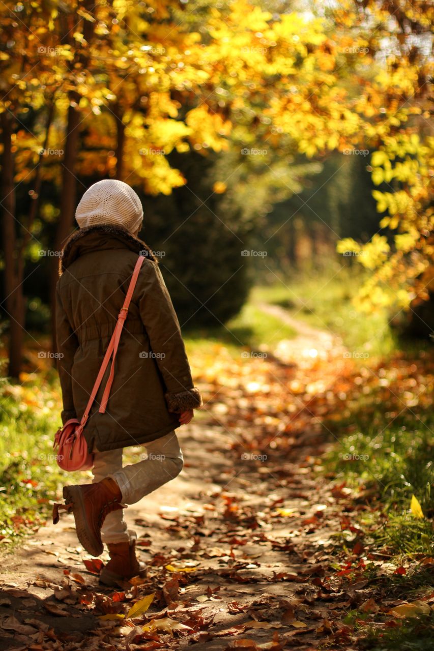 Little girl walks in the autumn park