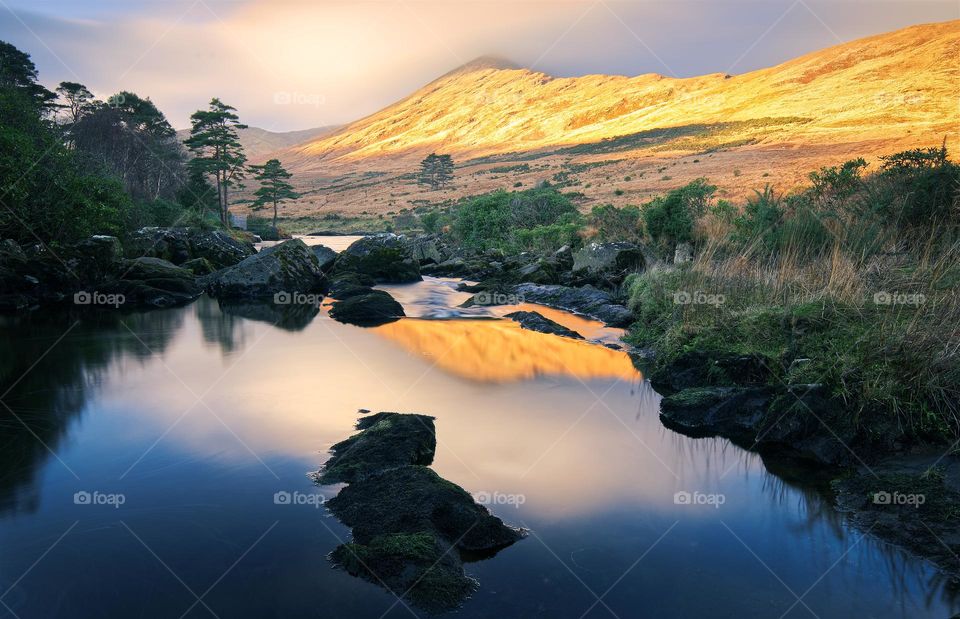 Beautiful landscape scenery of mountain illuminated with morning light reflected in river Erriff at Aesleagh in county Mayo, Ireland