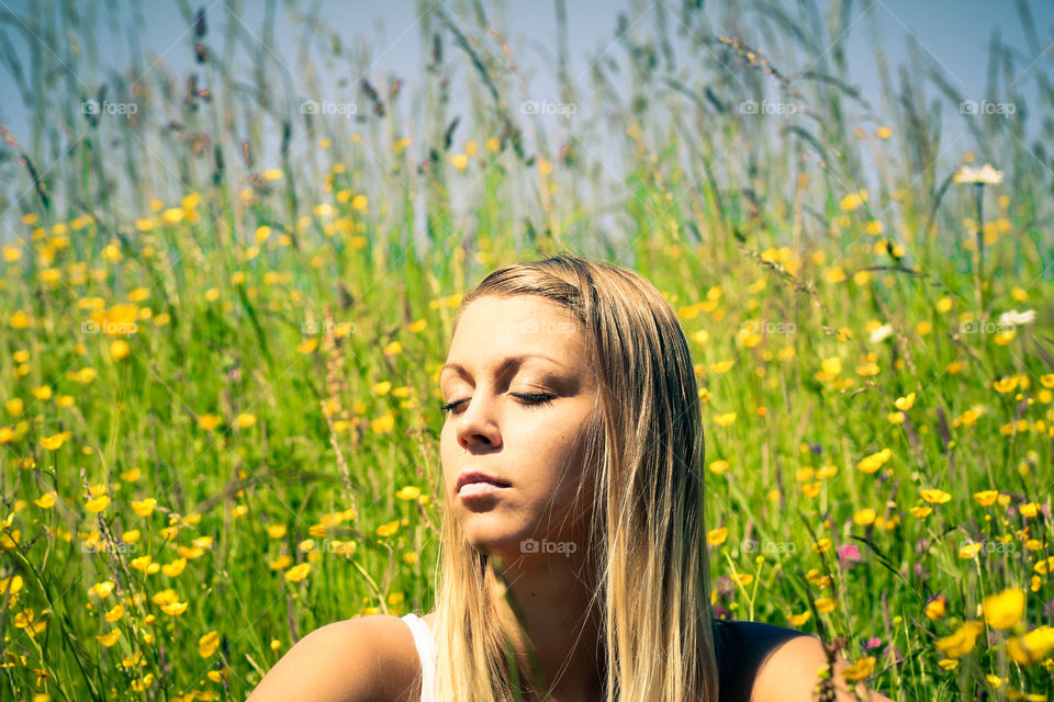 Woman with eye closed sitting in meadow