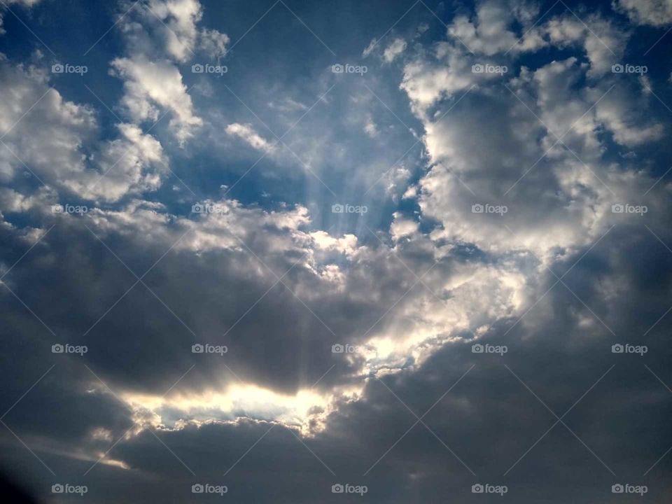 clouds at evening
hiding sun
sunrays running  through clouds
beautiful scenario