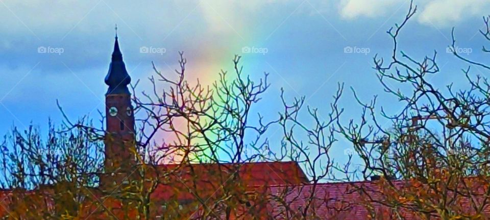 This photograph shows an unusually large and colorful rainbow over the “St Jacob Church” in “Straubing”, “Lower Bavaria”, Germany. It appeared one afternoon after a heavy downpour. 2024. Hypnotic Productions
