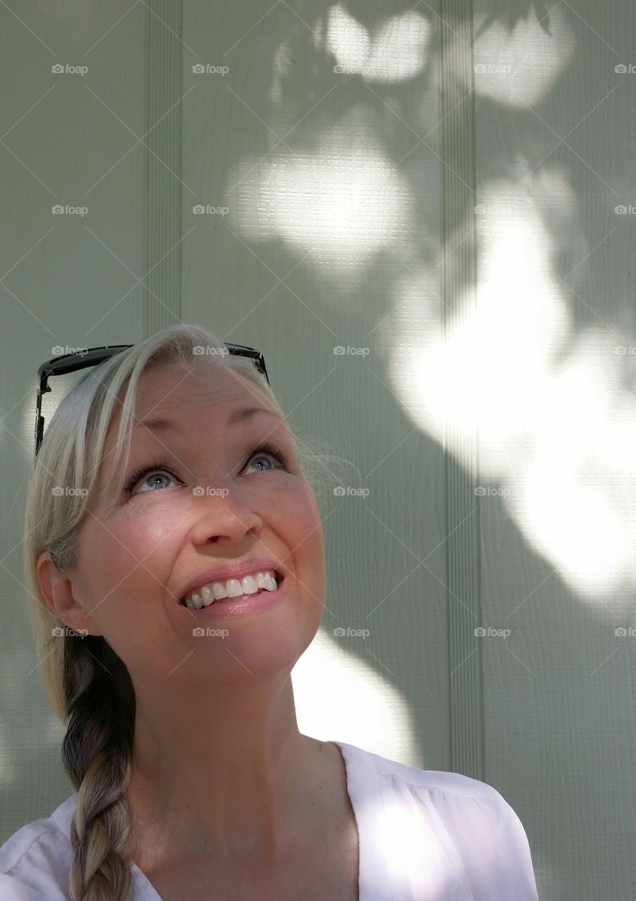 A woman looking up with the shadow of a tree in the background