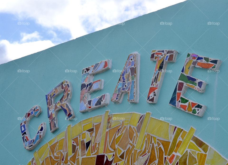 A blue wall with mosaic tile spelling the word CREATE
