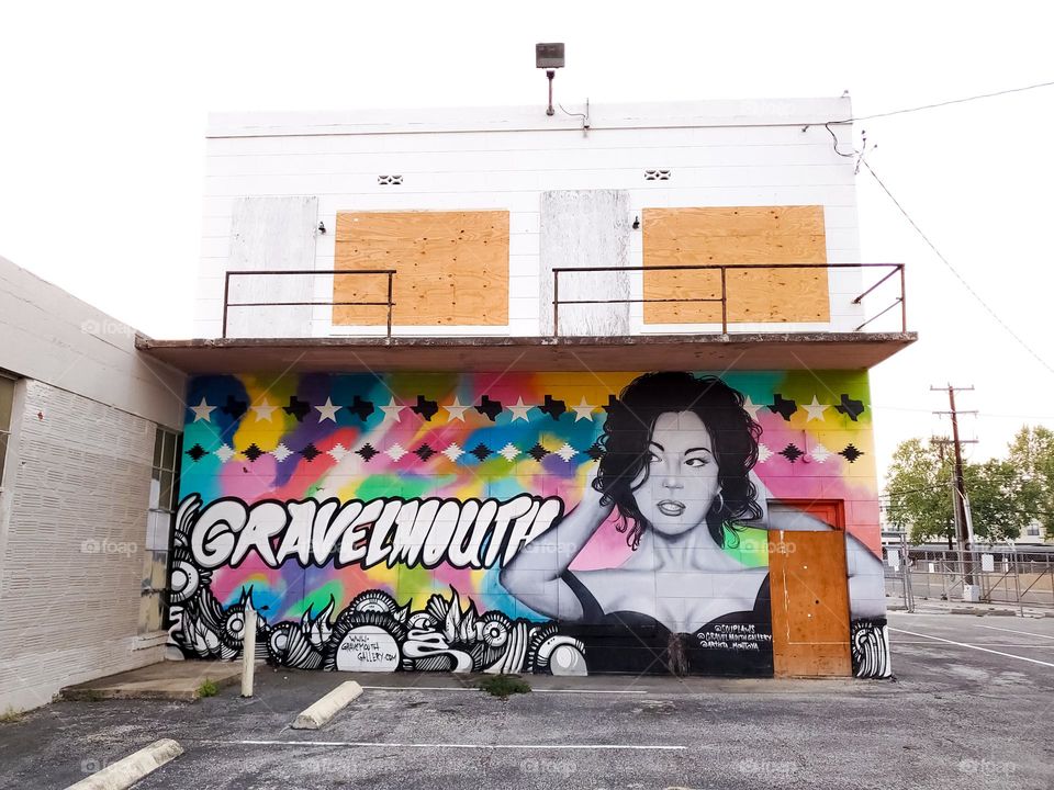 Visual urban street art: A portrait of a women painted in black and white surrounded by a bright colorful background.