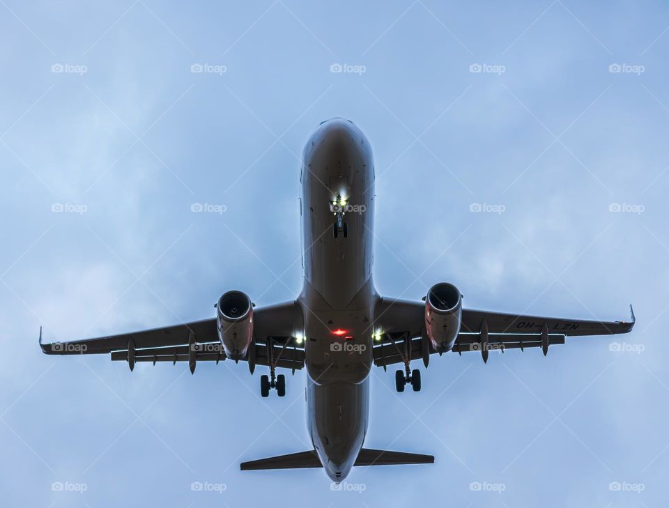 an airplane files through a cloudy sky with a red tail light