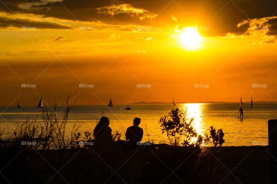 A relaxing evening on the beach with a golden sunset setting over the horizon.