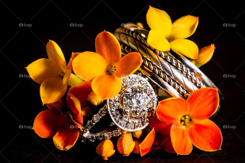 Macro image of wedding rings with diamonds and orange and yellow flowers