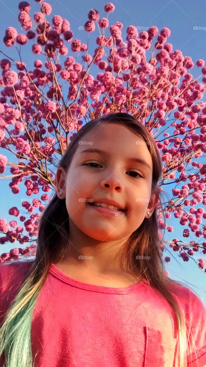 Girl under blue sky and pink flowers