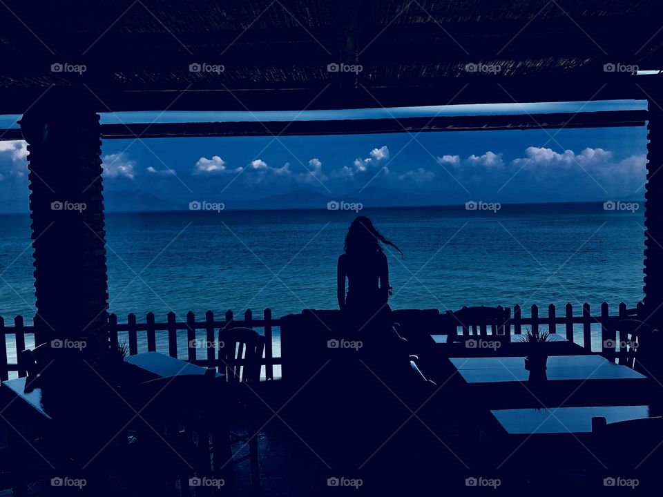 Restaurant with sea view in the evening. Woman looking at sea view.  The picture was taken in the evening so there are beautiful shadows