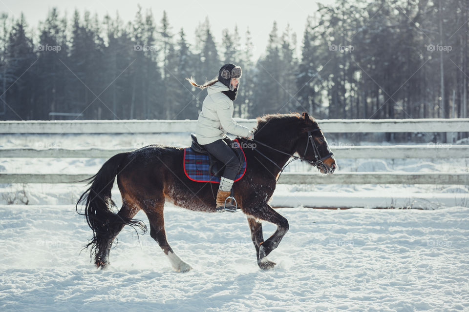 Teenage girl horseback jumping at cold winter day