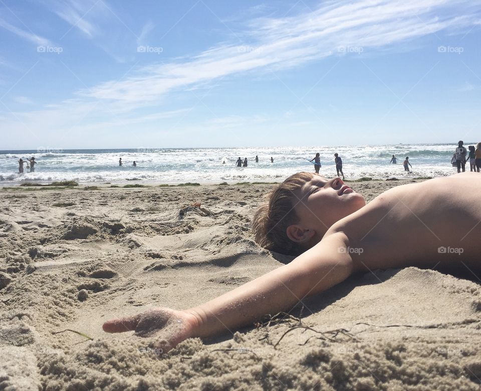 Boy lying on sandy beach