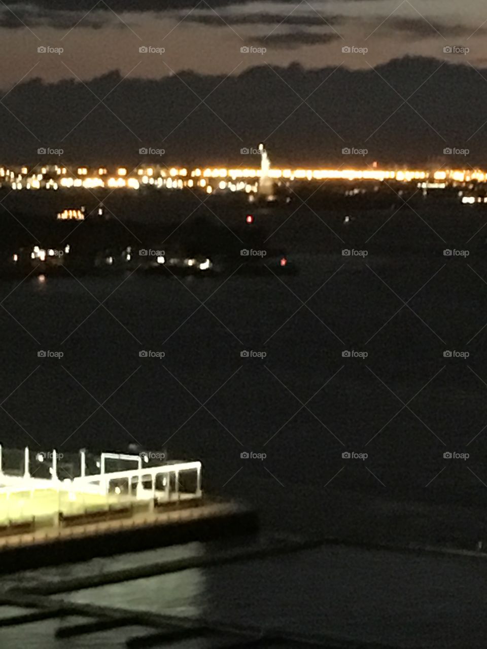 View of the illuminated railing of the terrace of the elite home on Pierrepoint Place in Brooklyn, NY and the lights of Manhattan at night in the distance. Photo was taken in September 2017. Hypnotic Productions