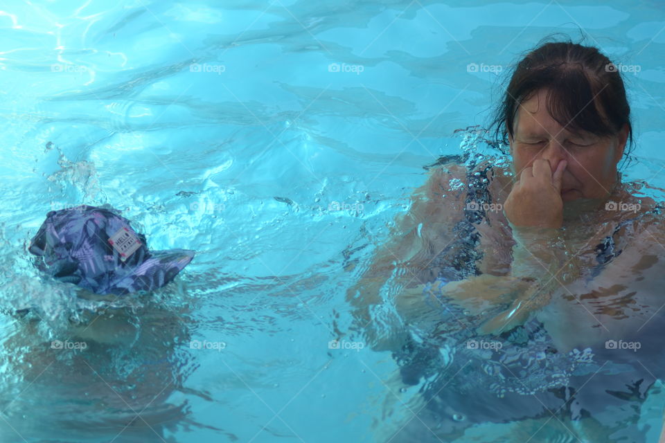 Woman in the swimming pool closing her nose