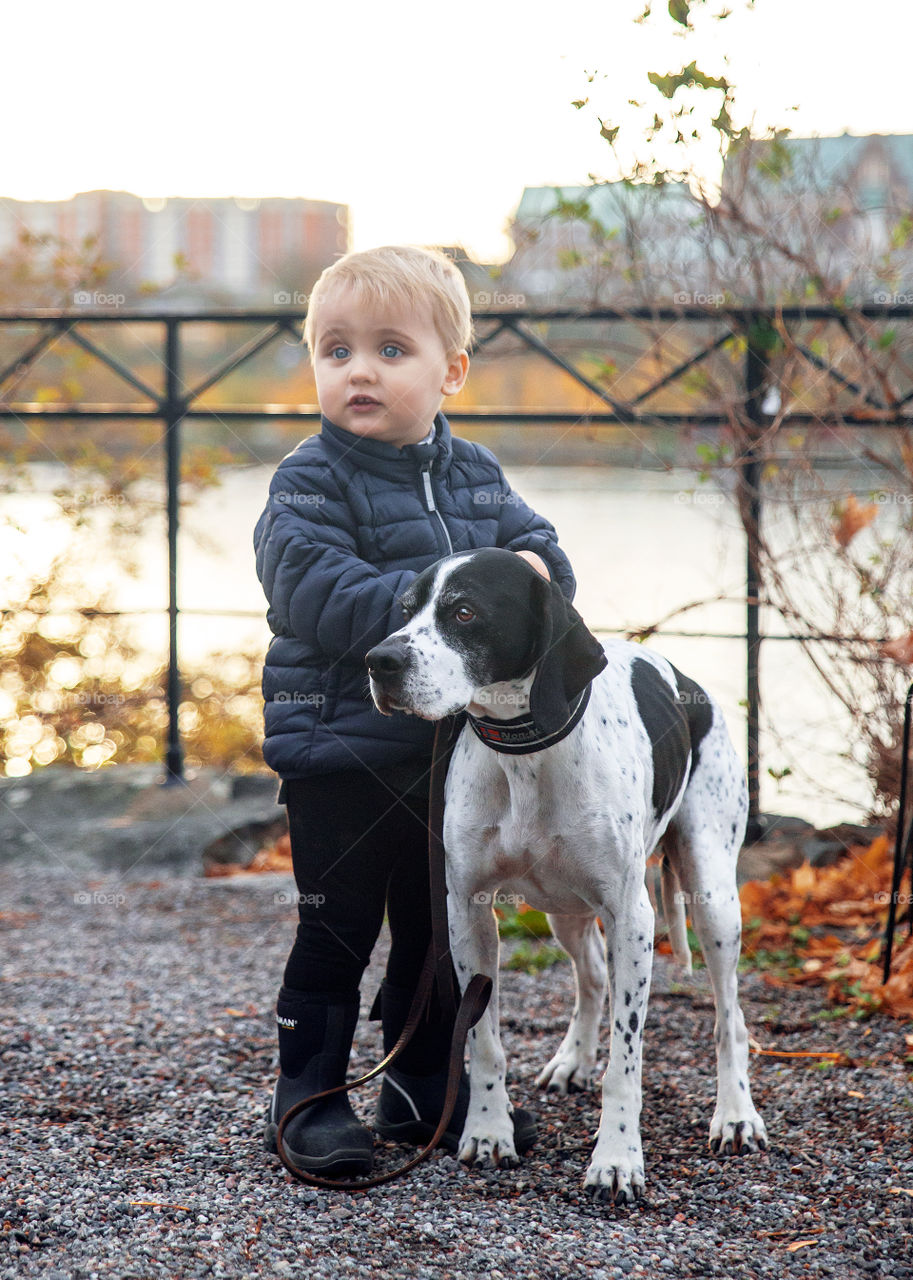 Cute Young boy with his beautiful pointer dog being best friends in autumn season