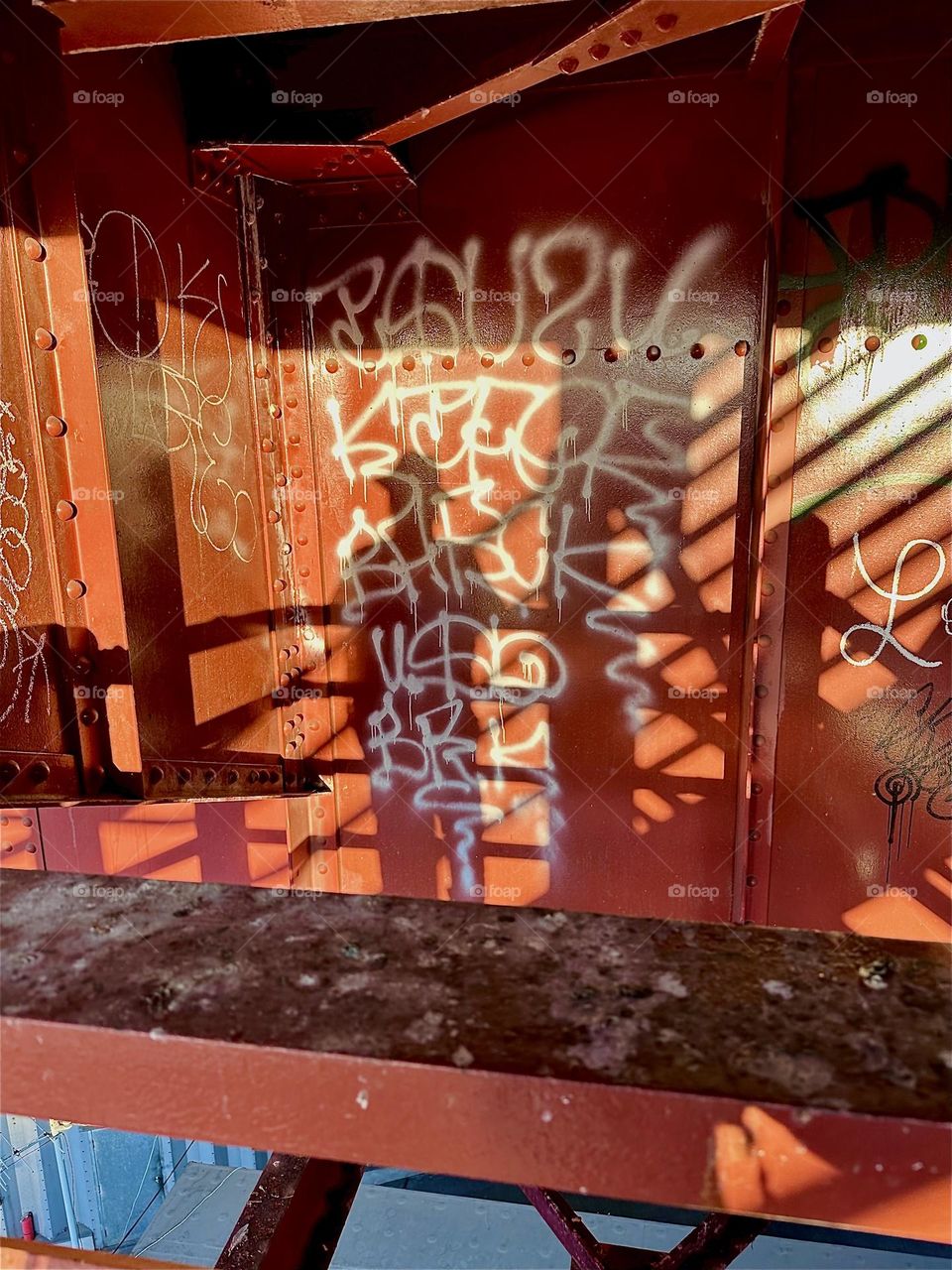 Interesting shadow patterns are forming on the red metal staircase of the „Pulaski Bridge“ at „Newtown Creek“ in LIC, Queens in the late afternoon sun as it begins to set. The person with the hat standing there is me. 2024. Hypnotic Productions