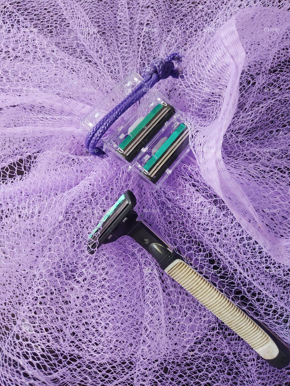 Gray razor, blade refill, purple netting background
