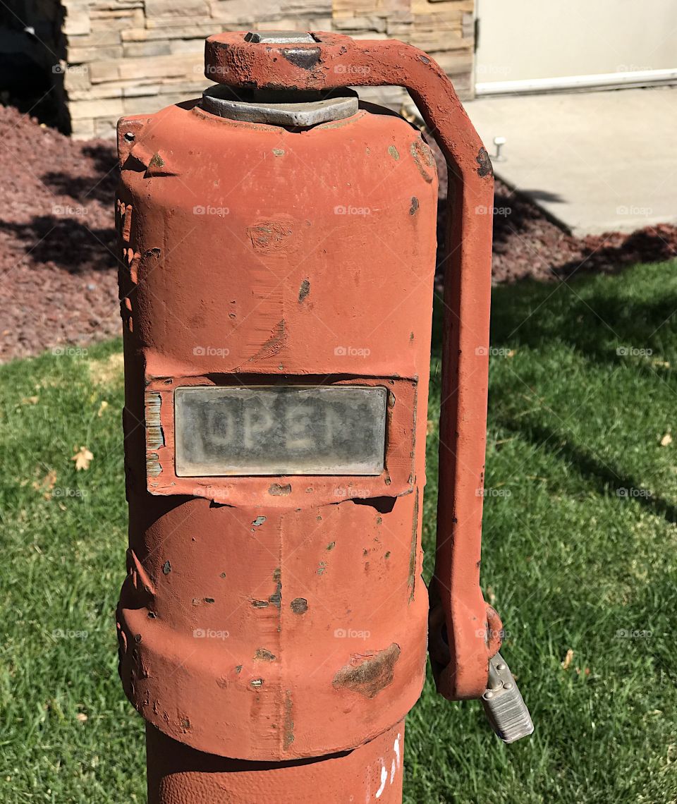 An industrial fire hydrant with worn and peeling paint covering rust all with an open indicator. 