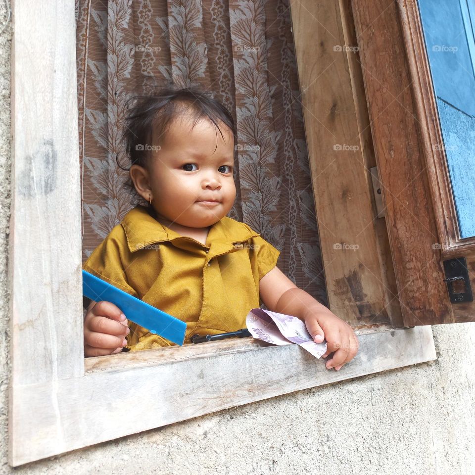 Sweet smile of toddler in the window of the house