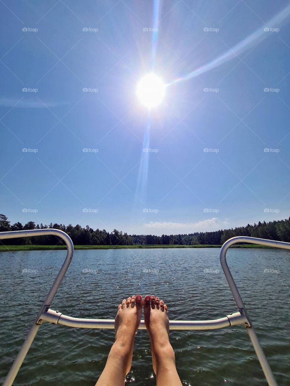  Bright summer day with clear high sun and lady feet on the fence of the boat