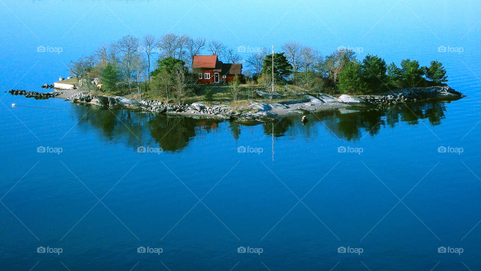 Small island with single red timber house in the archipelago cruising to Stockholm