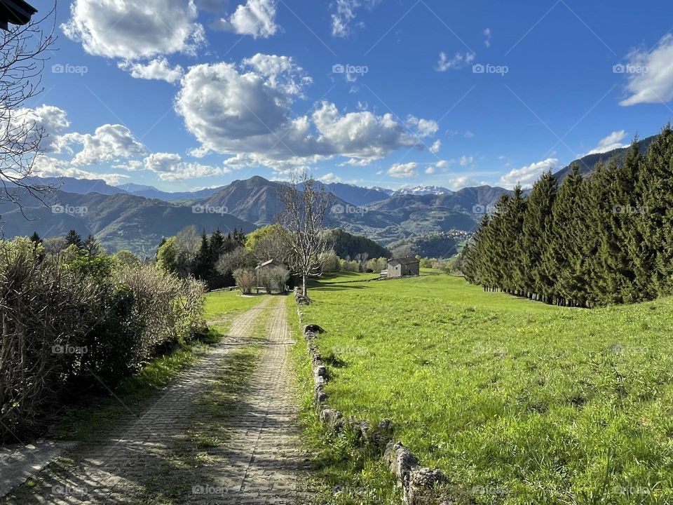 Mountain landscape view from the hiking trail along a big green lawn under a blue cloudy Sky 