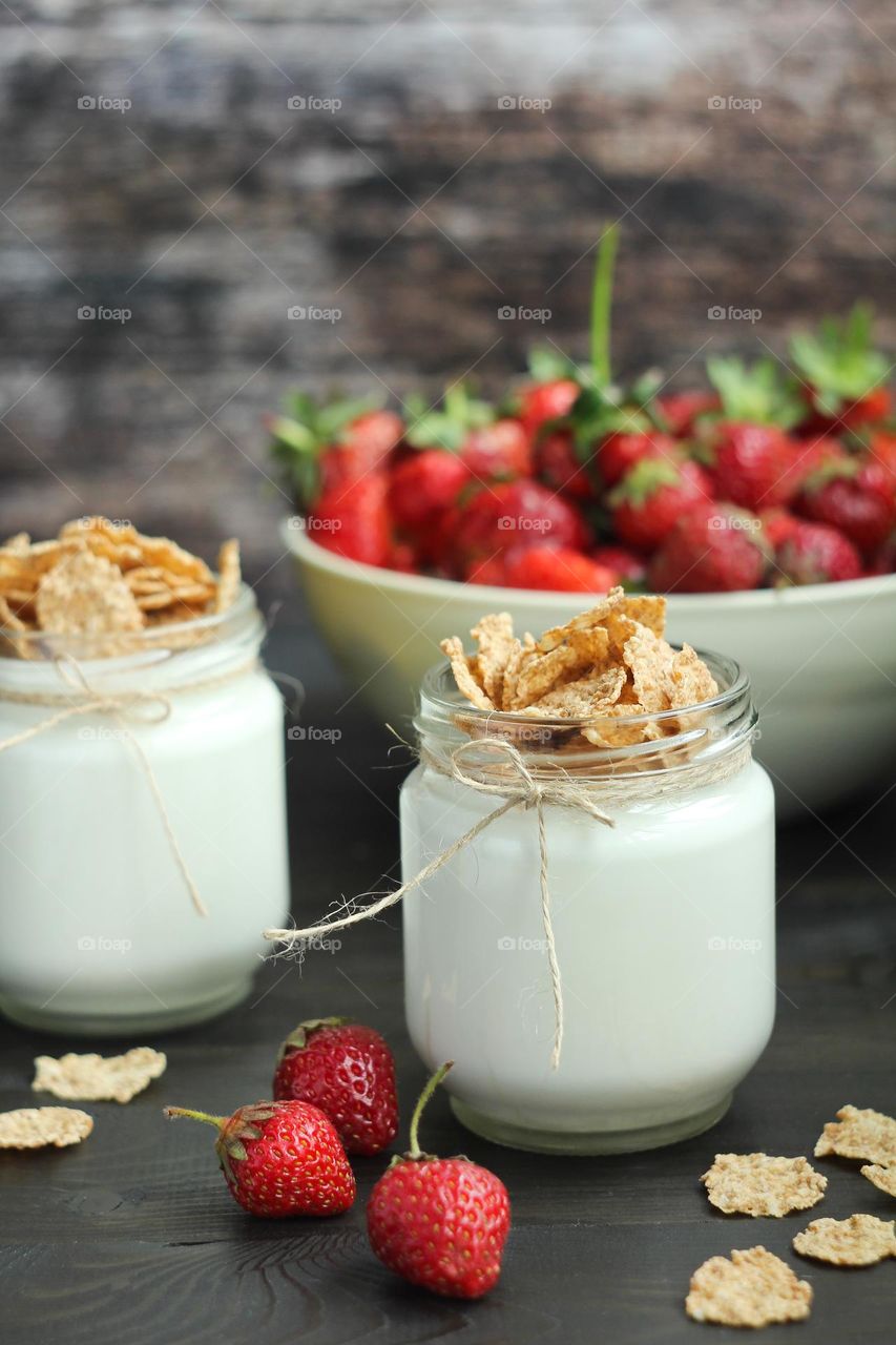 Yogurt with flakes and strawberries in a transparent jar