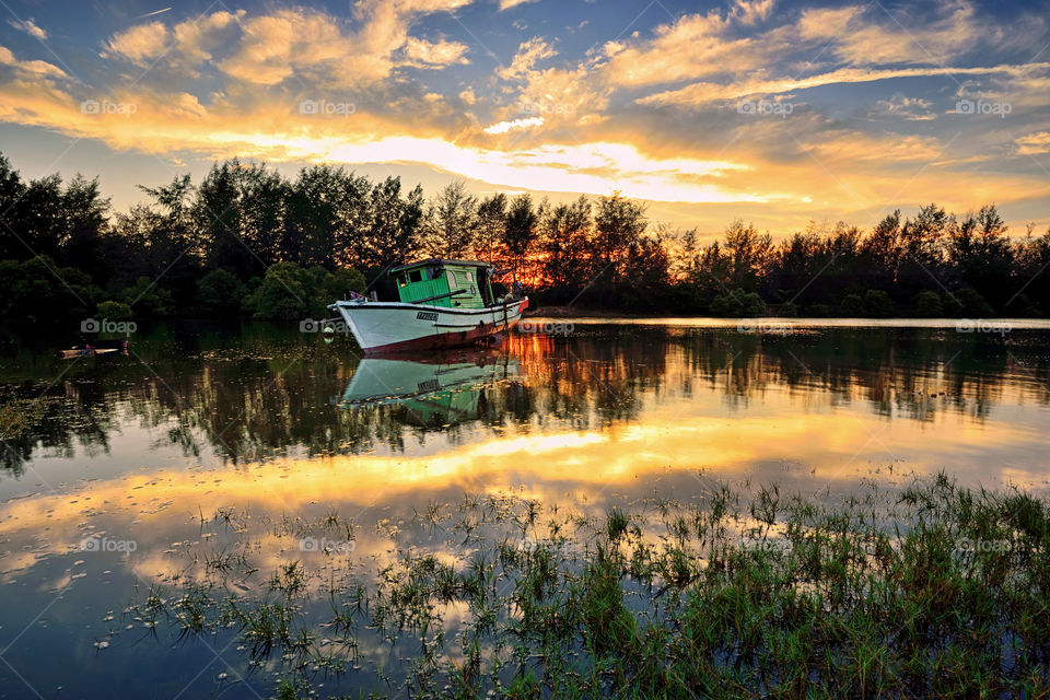 Abandoned. An abandoned boat at sunset with reflections of sky