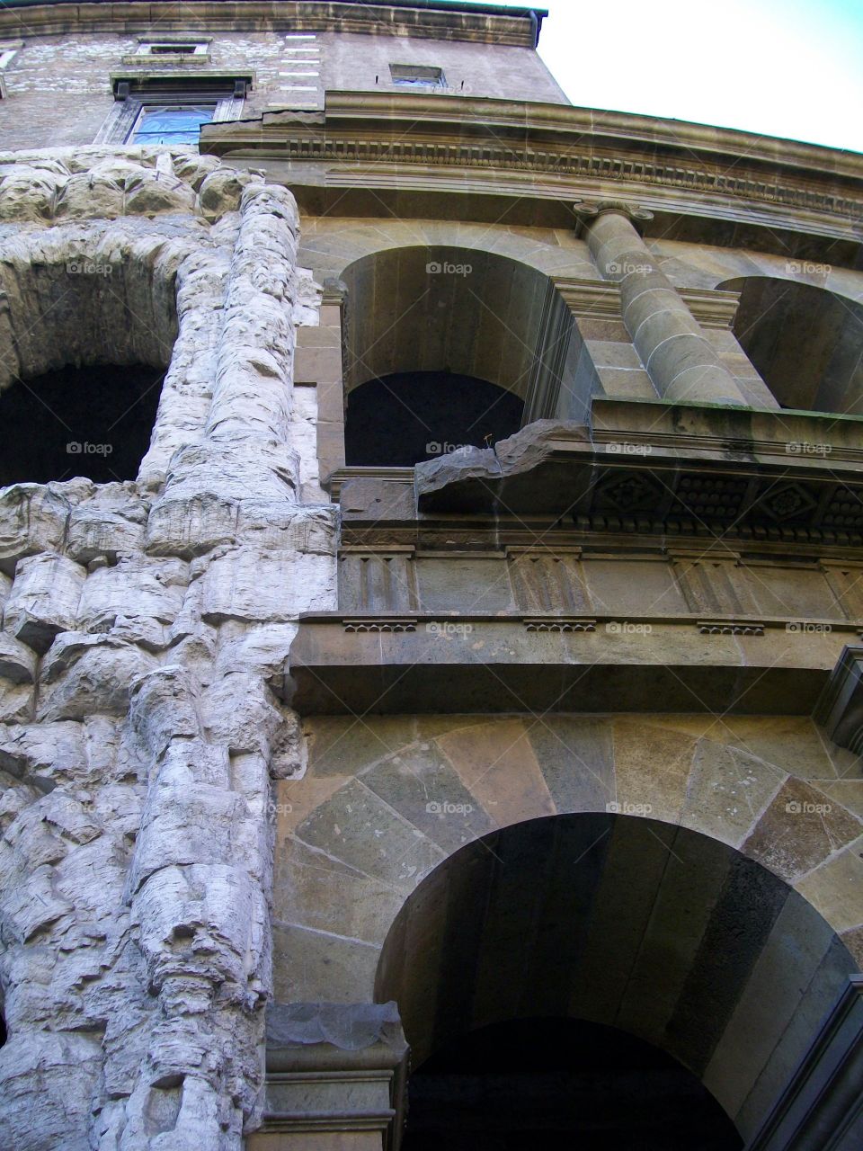 A close up of uncovered ancient ruins side by side with the modern reconstruction of the arches