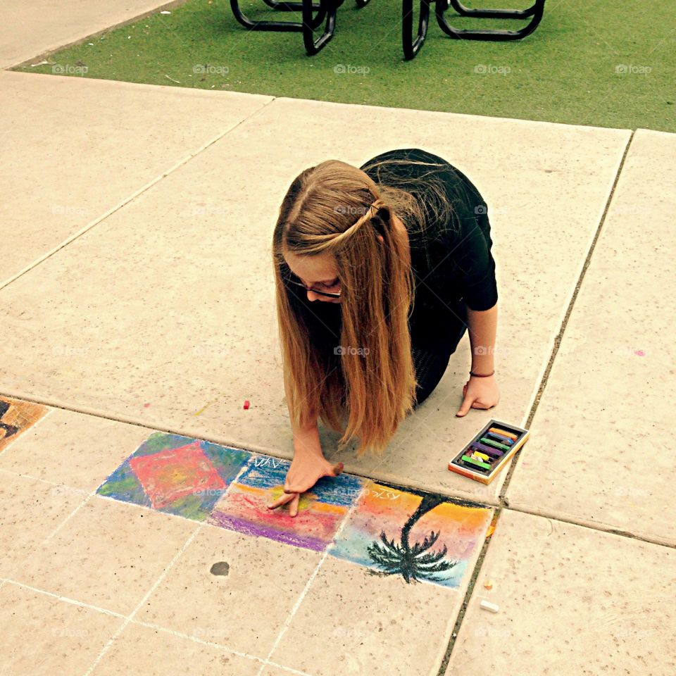 Teenager at the school painting on ground